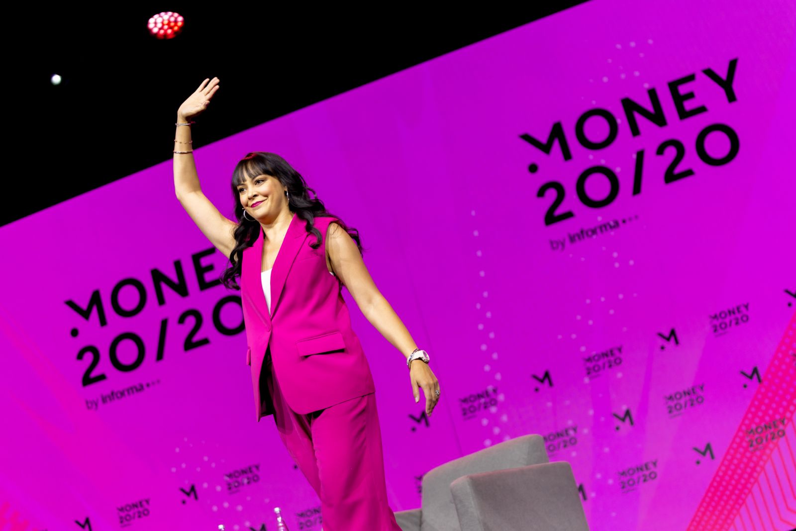 Speaker in a hot pink suit waving on the Money 20/20 Main Stage