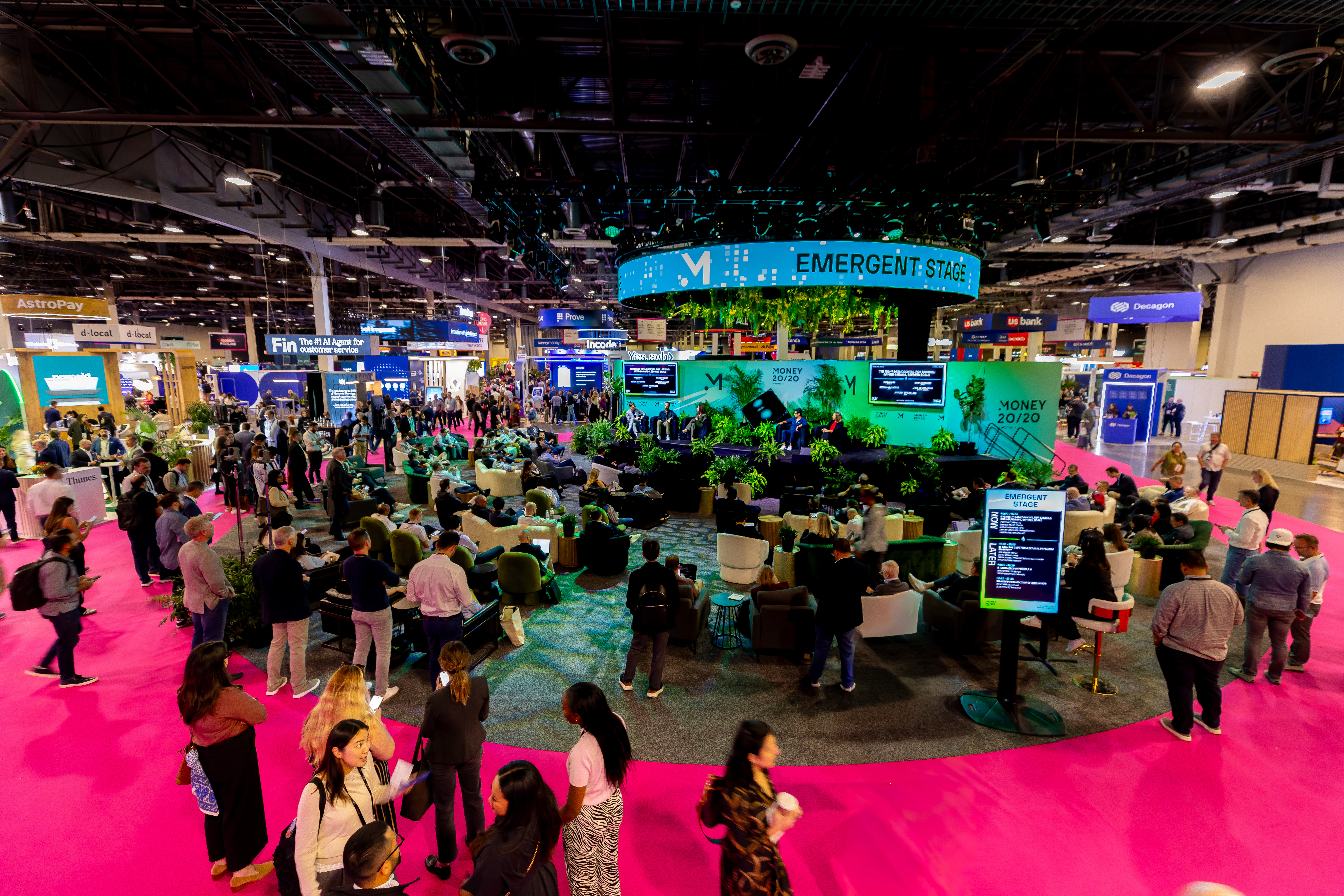 Hot pink expo floor, lounge seating in the round, and the Emergent Stage ring overhead at Money 20/20 USA 2025