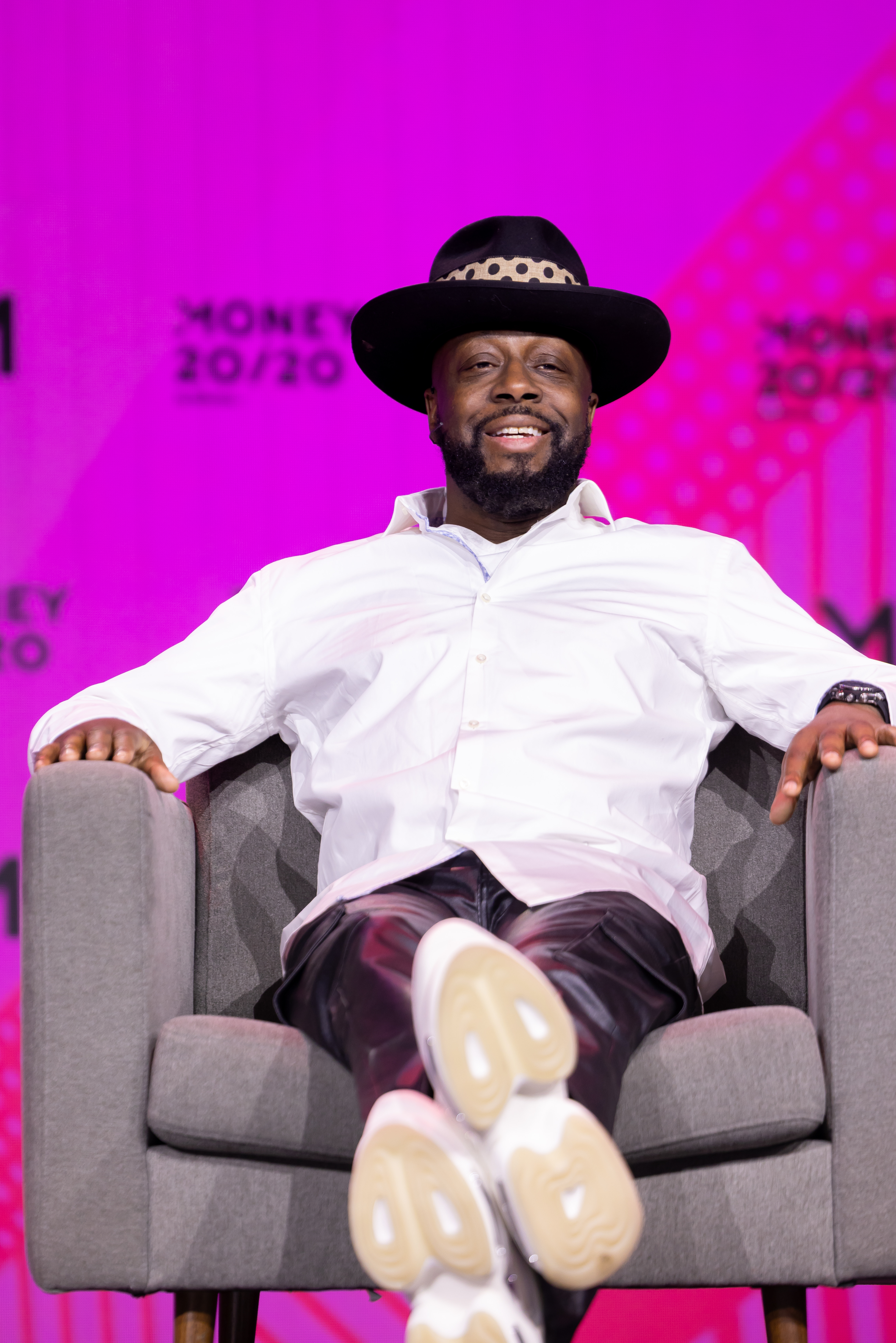 Wyclef Jean seated on the Main Stage in a wide-brim hat and white shirt