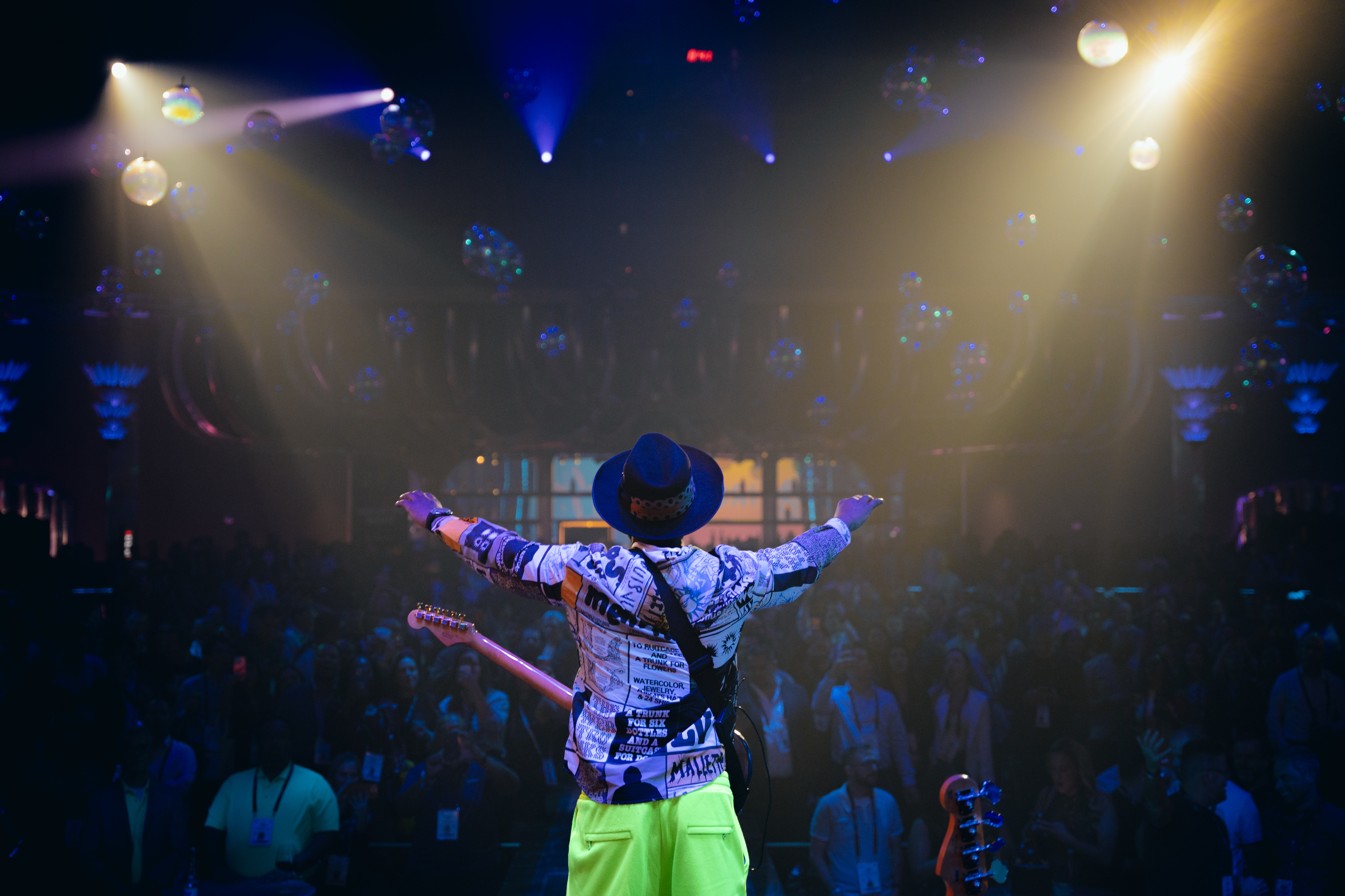 Performer at Industry Night, arms outstretched, disco balls overhead